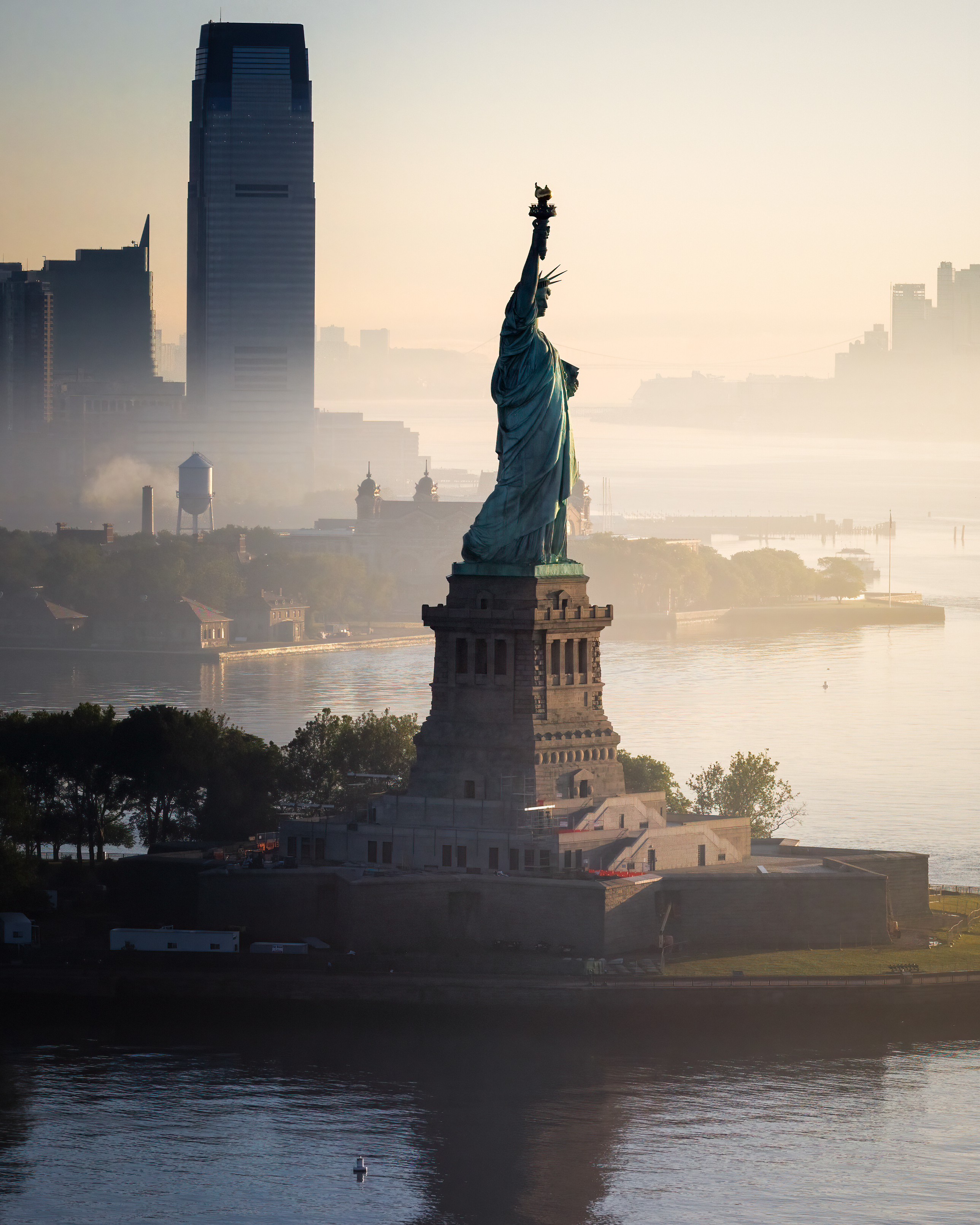 Aerial view of the Statue of Liberty at golden hour with New York City skyline